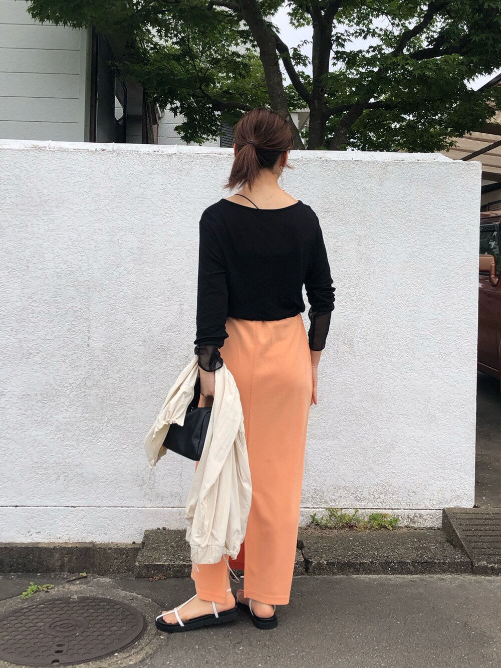 ブラック系のTシャツ/カットソー、オレンジ系のスカート、ホワイト系のサンダルを着用したレディースの夏コーディネートの3枚目の写真