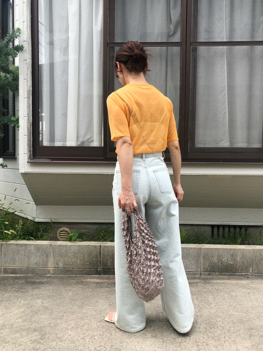 オレンジ系のニット/セーター、グレー系のエコバッグ/サブバッグ、その他のスマホケース/カバーを着用したレディースの夏コーディネートの3枚目の写真