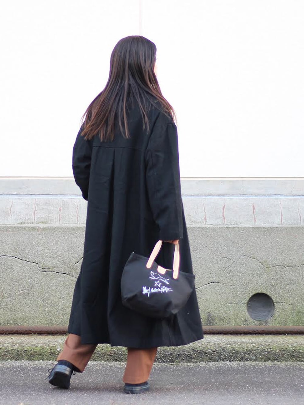 ブラック系のチェスターコート、ブラウン系のニット/セーター、ホワイト系のTシャツ/カットソーを着用したメンズの秋コーディネートの3枚目の写真