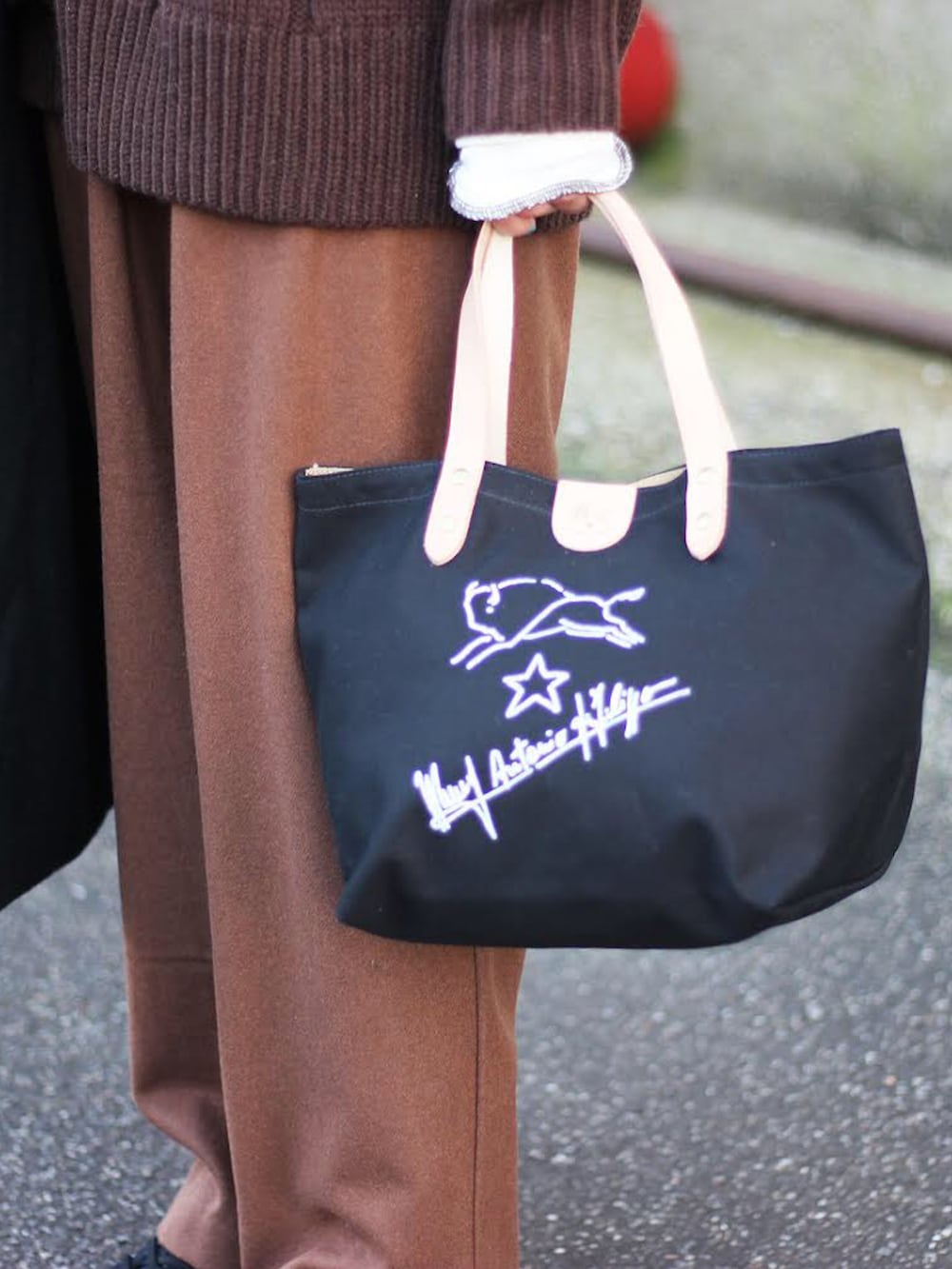 ブラック系のチェスターコート、ブラウン系のニット/セーター、ホワイト系のTシャツ/カットソーを着用したメンズの秋コーディネートの4枚目の写真