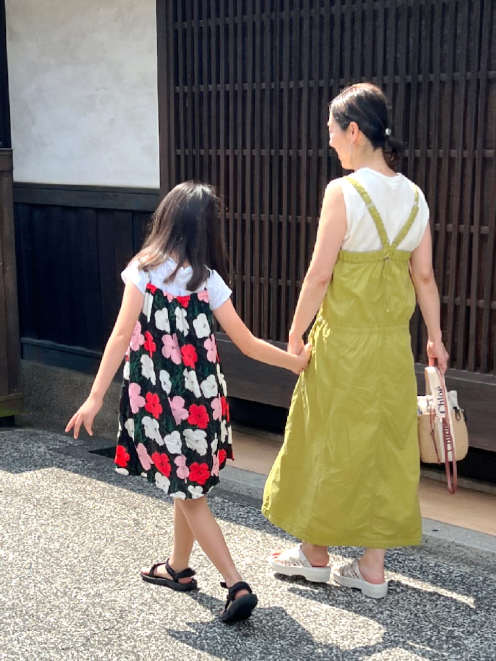ブラック系のサンダル、その他のワンピース、イエロー系のジャンパースカートを着用したレディースの夏コーディネートの2枚目の写真