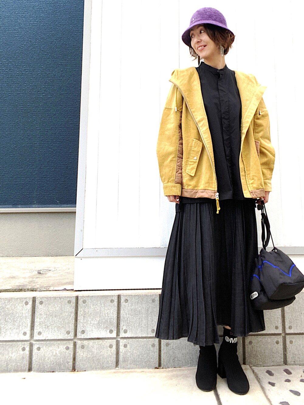 ブラック系のデニムスカート、ブラック系のブーツ、ブルー系のショルダーバッグを着用したレディースの秋コーディネートの2枚目の写真