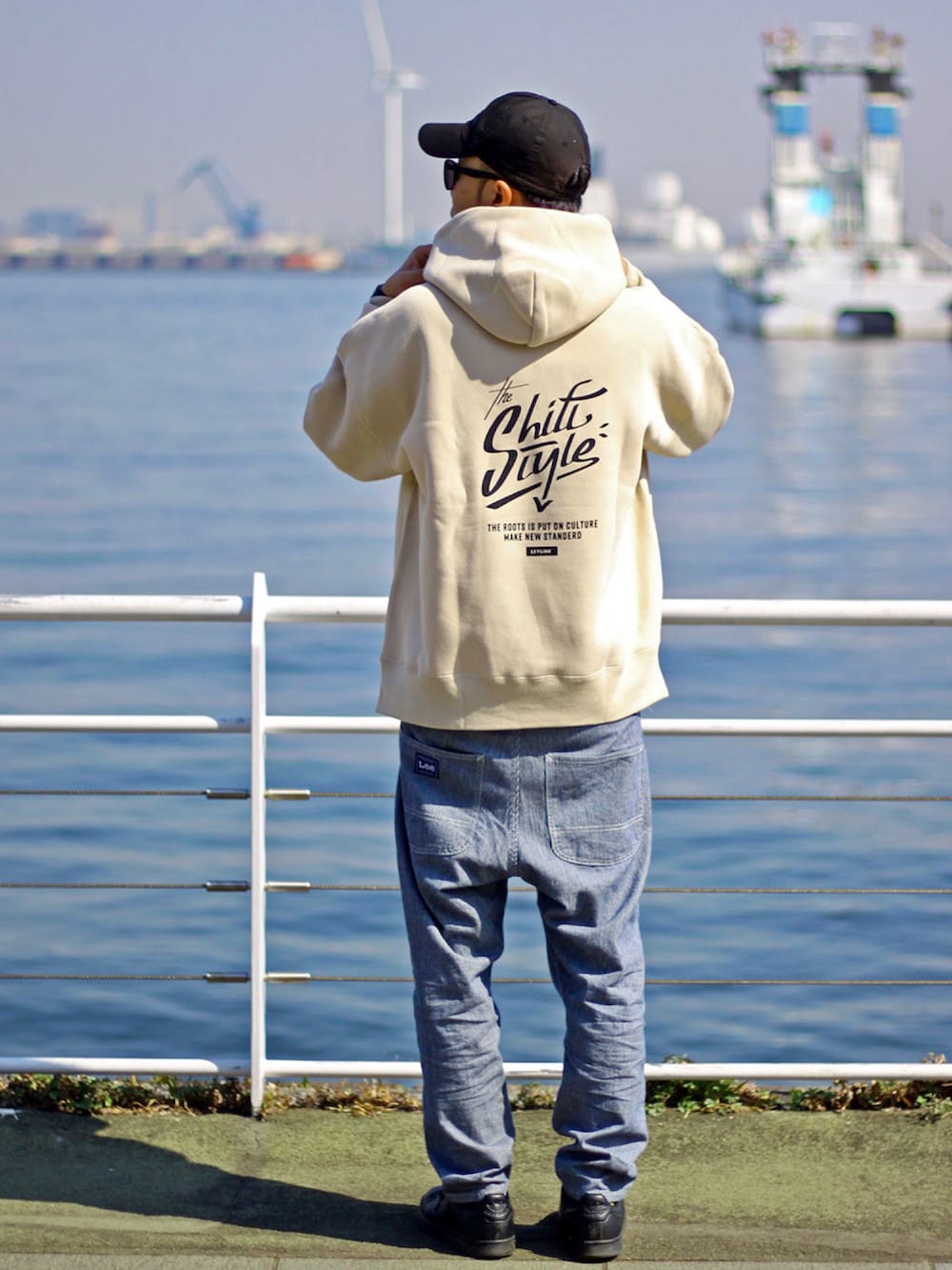 ベージュ系のパーカー、ホワイト系のデニムパンツ、ブラック系のスニーカーを着用したメンズの春コーディネートの2枚目の写真