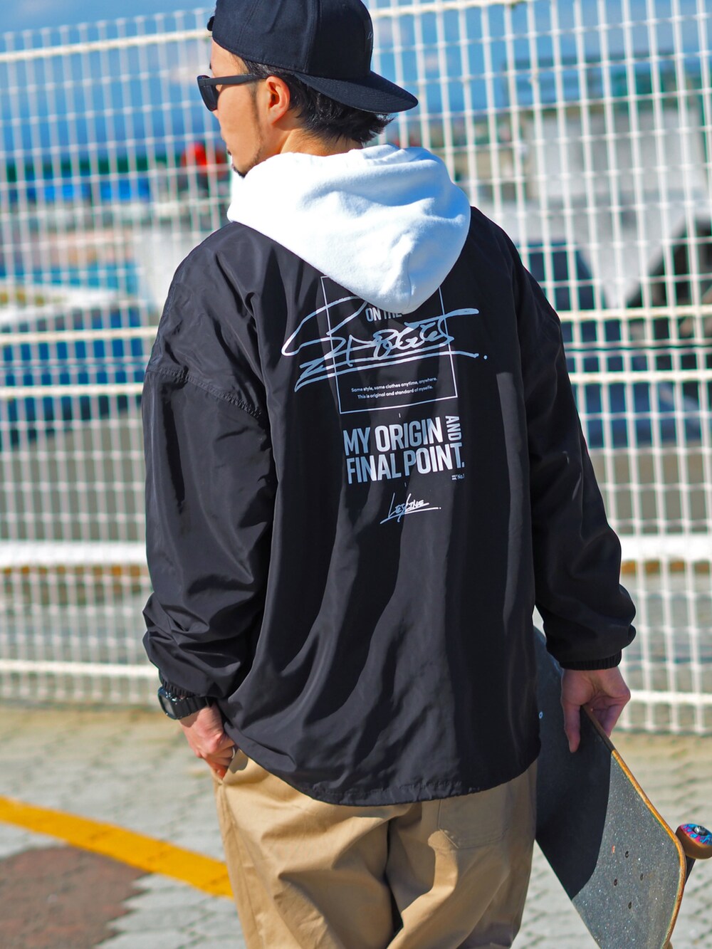 ブラック系のナイロンジャケット、ホワイト系のパーカー、ブラック系のスニーカーを着用したメンズの冬コーディネートの2枚目の写真