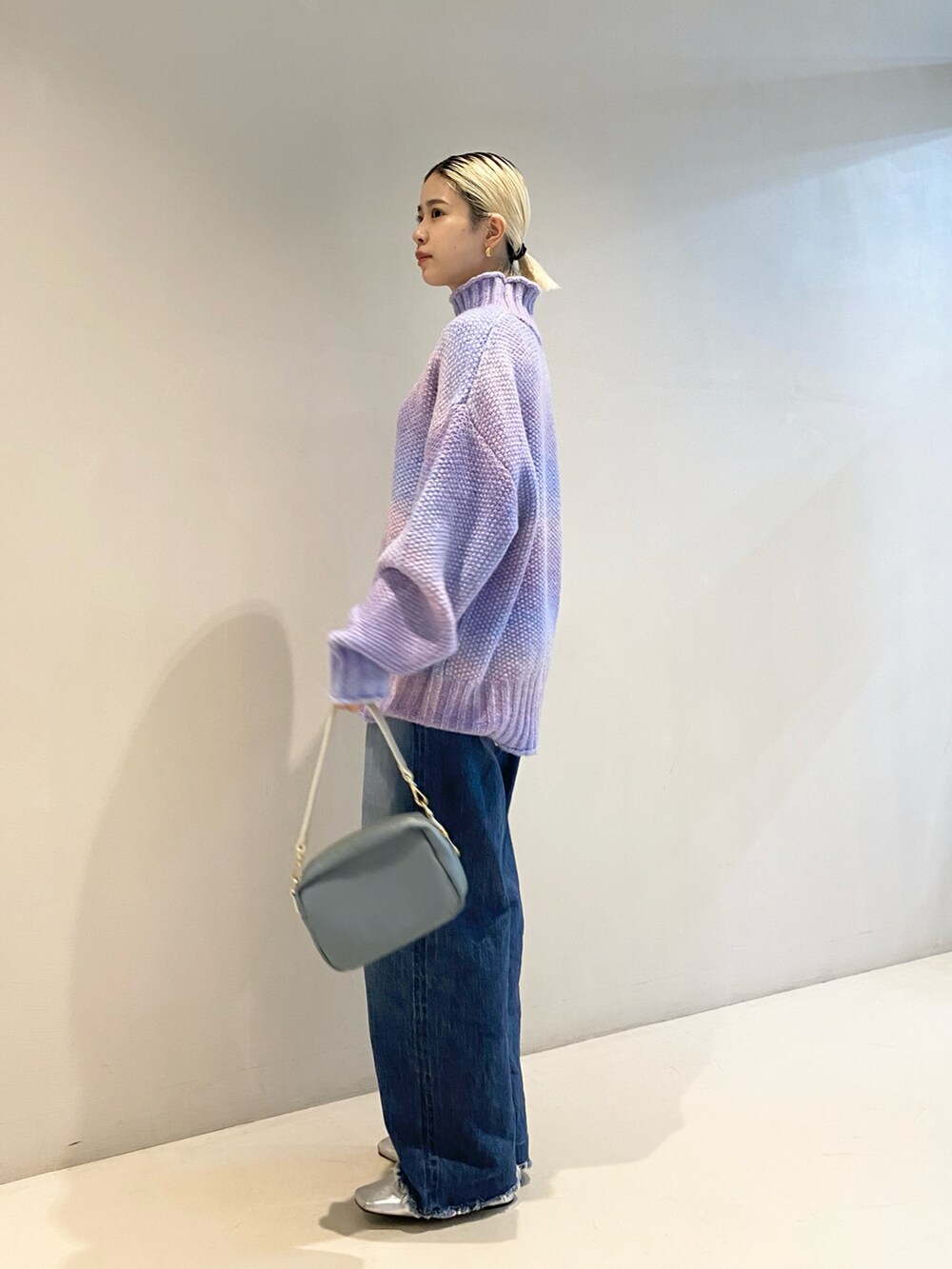 パープル系のニット/セーター、ブルー系のバッグ、シルバー系のパンプスを着用したレディースの秋コーディネートの2枚目の写真