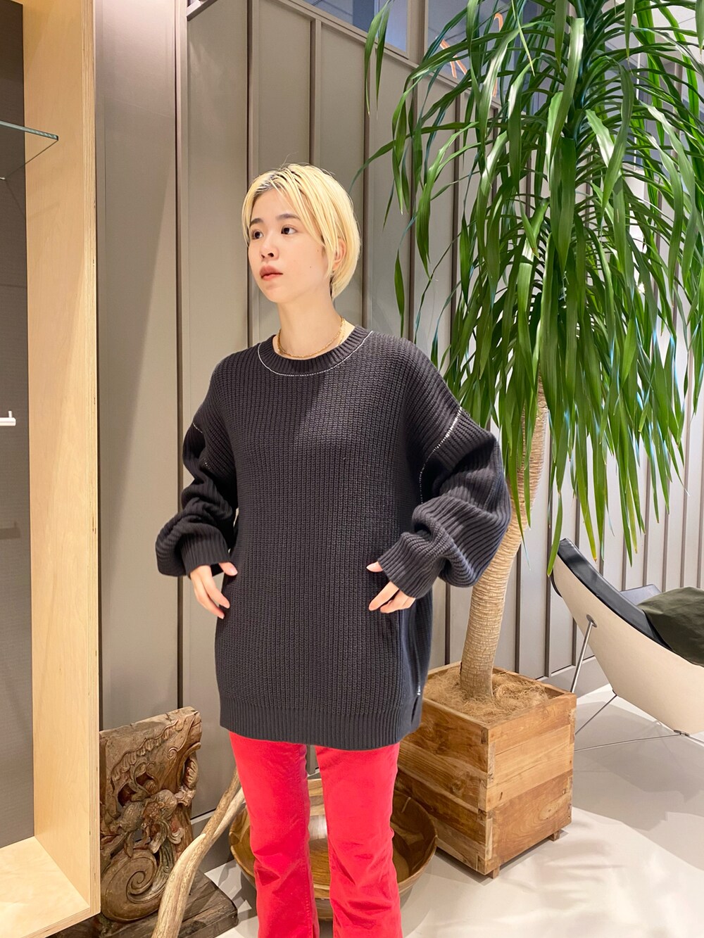 グリーン系のミリタリージャケット、レッド系のデニムパンツ、ブラック系のニット/セーターを着用したレディースの冬コーディネートの4枚目の写真