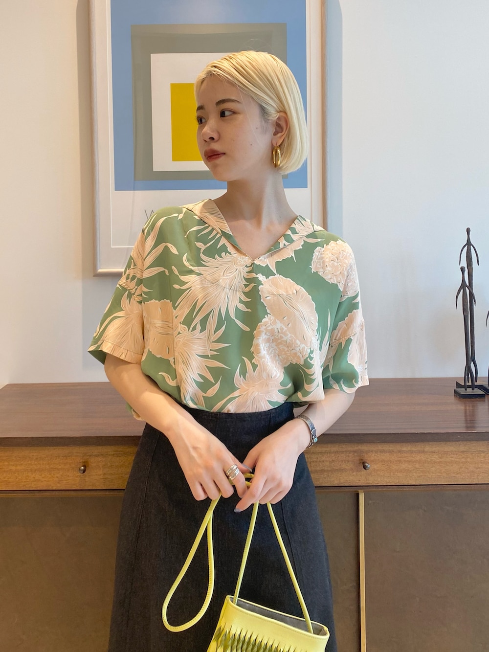 グリーン系のシャツ/ブラウス、ブラック系のスカート、ゴールド系のピアス（両耳用）を着用したレディースの春コーディネートの2枚目の写真