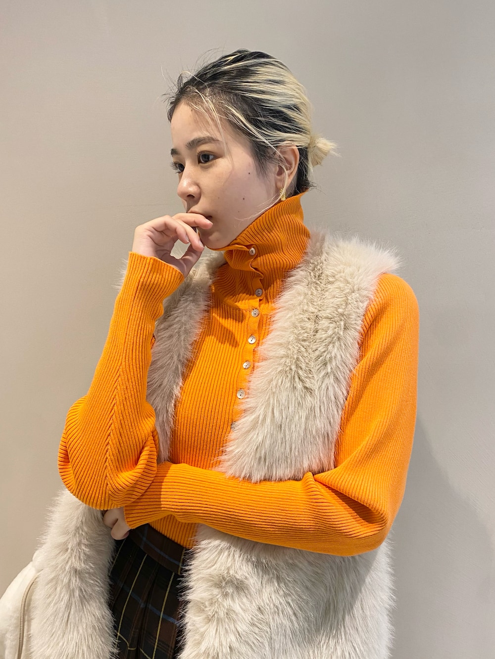 オレンジ系のニット/セーター、ホワイト系のベスト、ブラウン系のスカートを着用したレディースの秋コーディネートの2枚目の写真