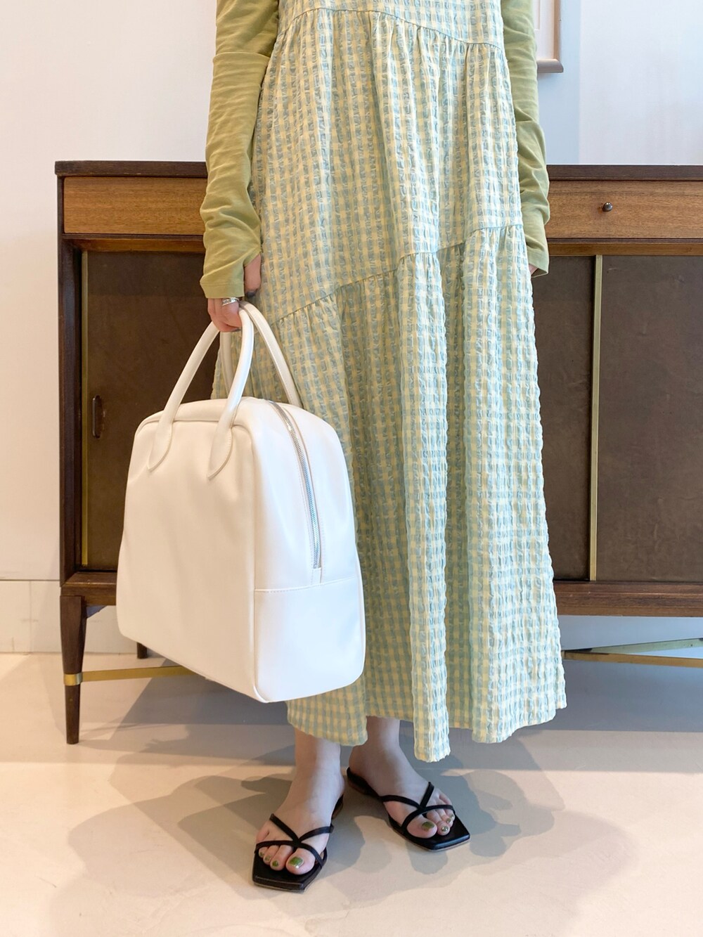 グリーン系のTシャツ/カットソー、イエロー系のワンピース、ホワイト系のボストンバッグを着用したレディースの春コーディネートの4枚目の写真