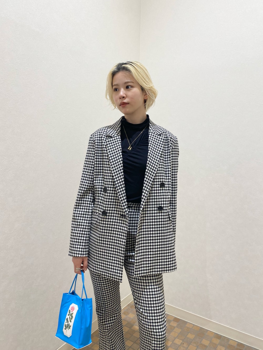 ブラック系のテーラードジャケット、ブラック系のその他パンツ、ブルー系のトートバッグを着用したレディースの冬コーディネートの2枚目の写真