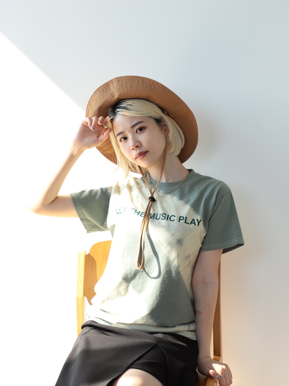 グリーン系のTシャツ/カットソー、ブラック系のスカート、ブラック系のサンダルを着用したレディースの夏コーディネートの2枚目の写真