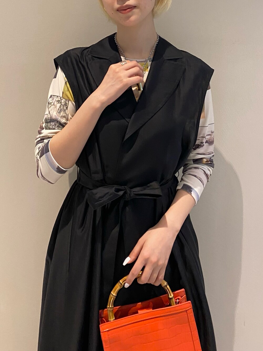 ブラック系のベスト、ホワイト系のTシャツ/カットソー、オレンジ系のトートバッグを着用したレディースの冬コーディネートの2枚目の写真