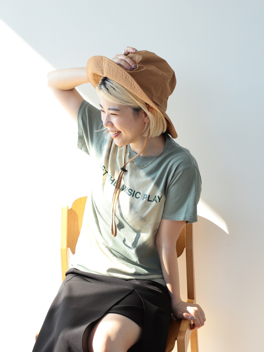 グリーン系のTシャツ/カットソー、ブラック系のスカート、ブラック系のサンダルを着用したレディースの夏コーディネートの3枚目の写真