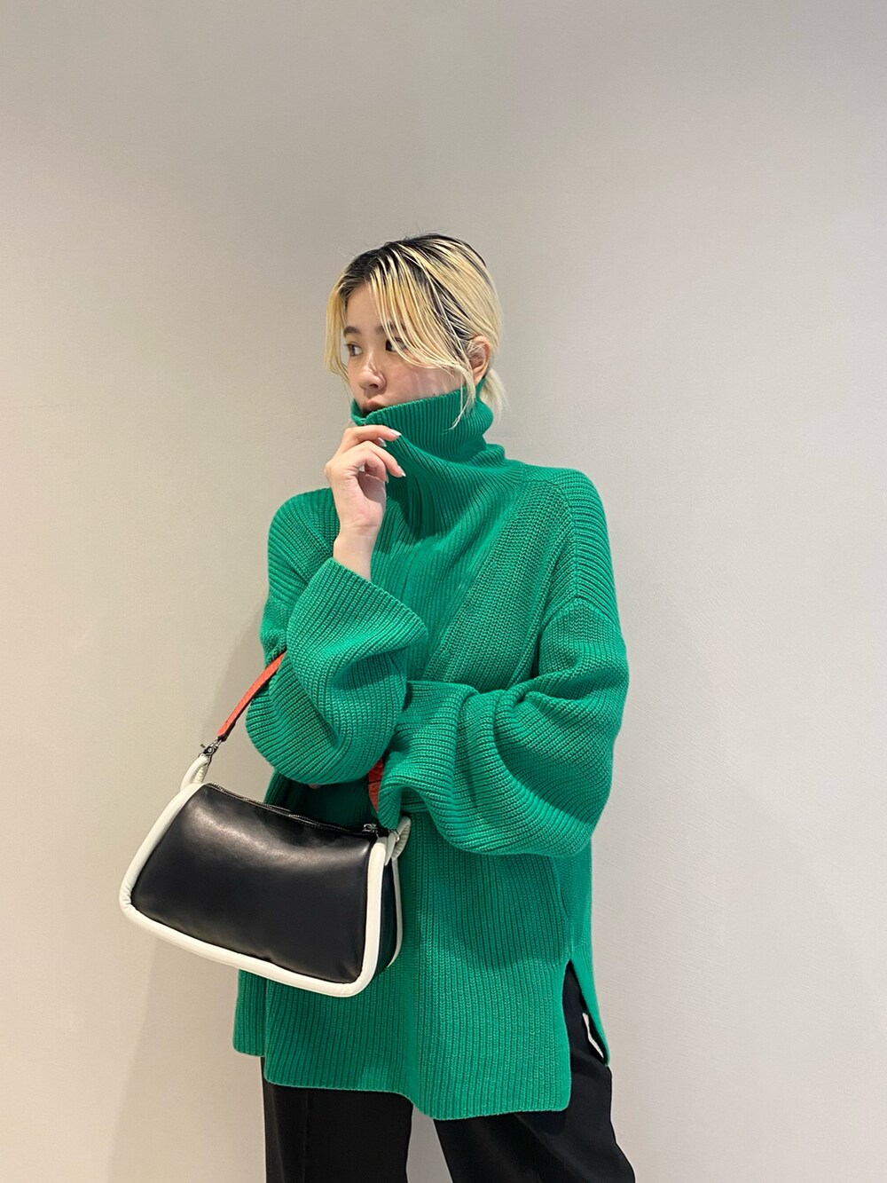 グリーン系のニット/セーター、ブラック系のショルダーバッグ、ブラック系のスラックスを着用したレディースの冬コーディネートの3枚目の写真
