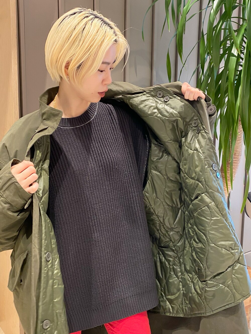 グリーン系のミリタリージャケット、レッド系のデニムパンツ、ブラック系のニット/セーターを着用したレディースの冬コーディネートの3枚目の写真