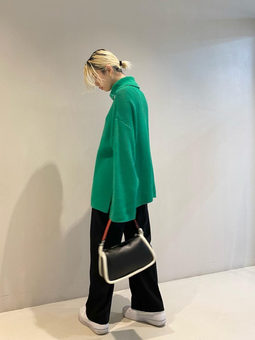 グリーン系のニット/セーター、ブラック系のショルダーバッグ、ブラック系のスラックスを着用したレディースの冬コーディネートの2枚目の写真