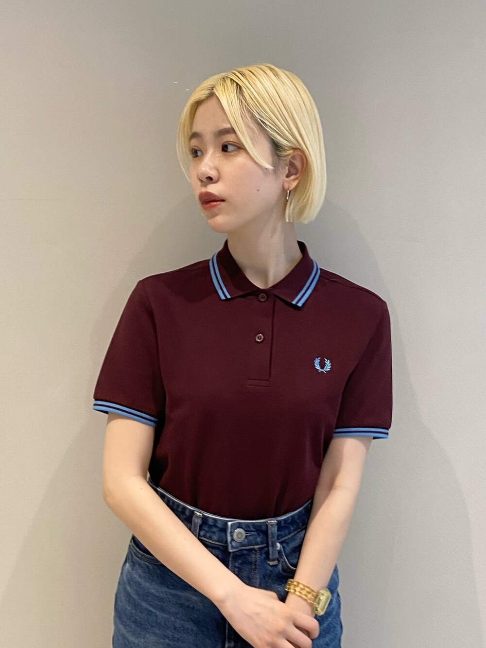 レッド系のポロシャツ、ブルー系のデニムスカート、ホワイト系のスニーカーを着用したレディースの冬コーディネートの3枚目の写真