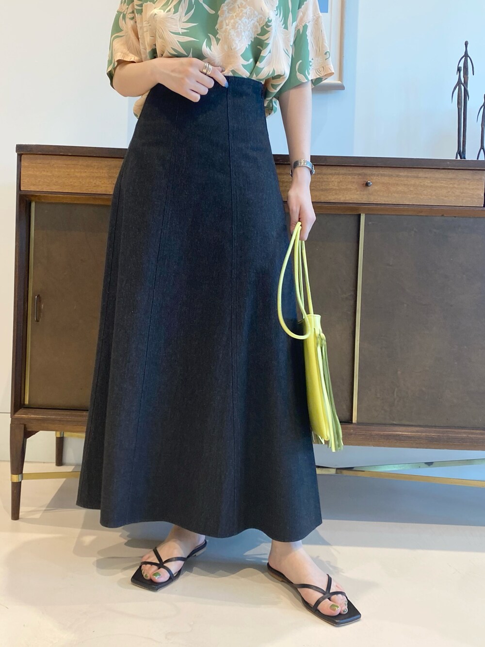 グリーン系のシャツ/ブラウス、ブラック系のスカート、ゴールド系のピアス（両耳用）を着用したレディースの春コーディネートの3枚目の写真