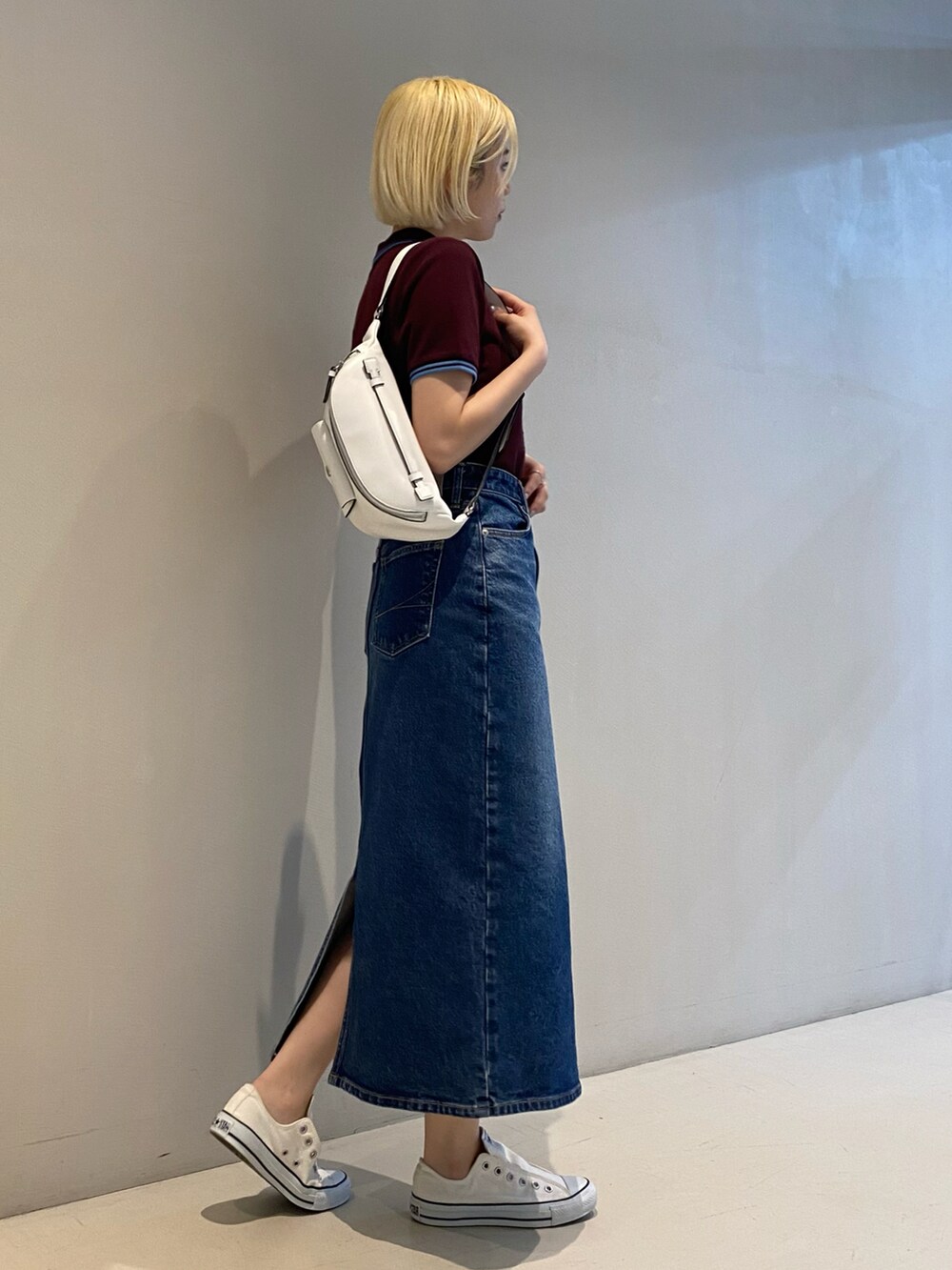 レッド系のポロシャツ、ブルー系のデニムスカート、ホワイト系のスニーカーを着用したレディースの冬コーディネートの2枚目の写真