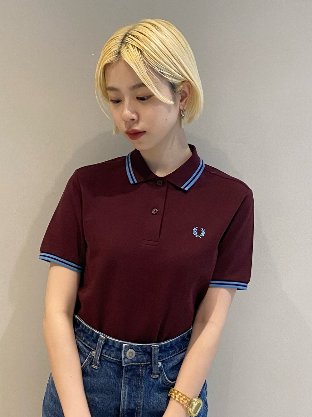 レッド系のポロシャツ、ブルー系のデニムスカート、ホワイト系のスニーカーを着用したレディースの冬コーディネートの4枚目の写真