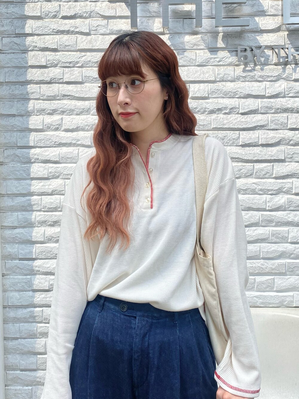レッド系のスニーカー、ブルー系のパンツ、ホワイト系のTシャツ/カットソーを着用したレディースの秋コーディネートの2枚目の写真