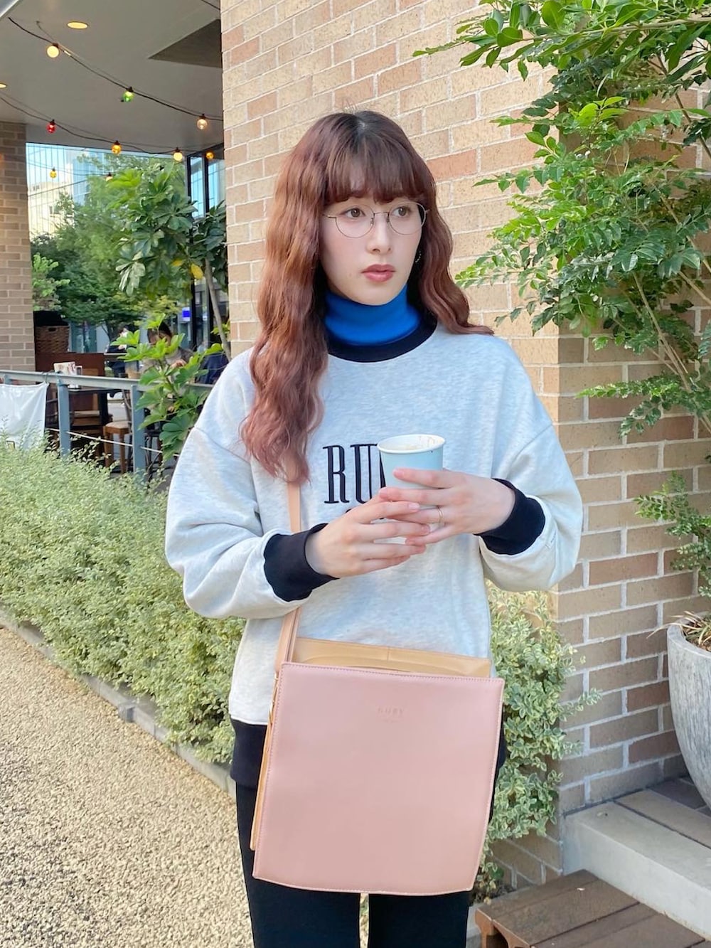 ブラック系のパンツ、ブラック系のスニーカー、ピンク系のショルダーバッグを着用したレディースの秋コーディネートの2枚目の写真