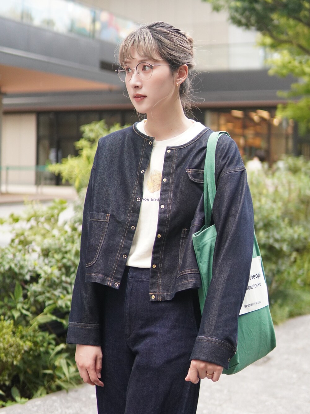 ブルー系のデニムジャケット、グリーン系のトートバッグ、ホワイト系のTシャツ/カットソーを着用したレディースの秋コーディネートの3枚目の写真