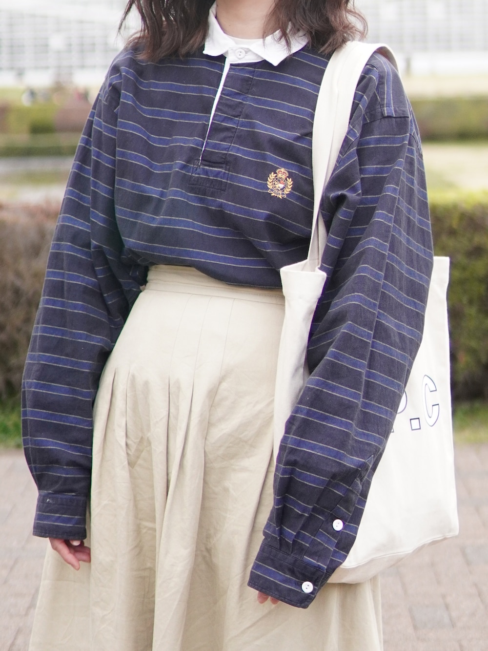 ベージュ系のスカート、ブラウン系のローファー、ブラック系のトートバッグを着用したレディースの春コーディネートの4枚目の写真