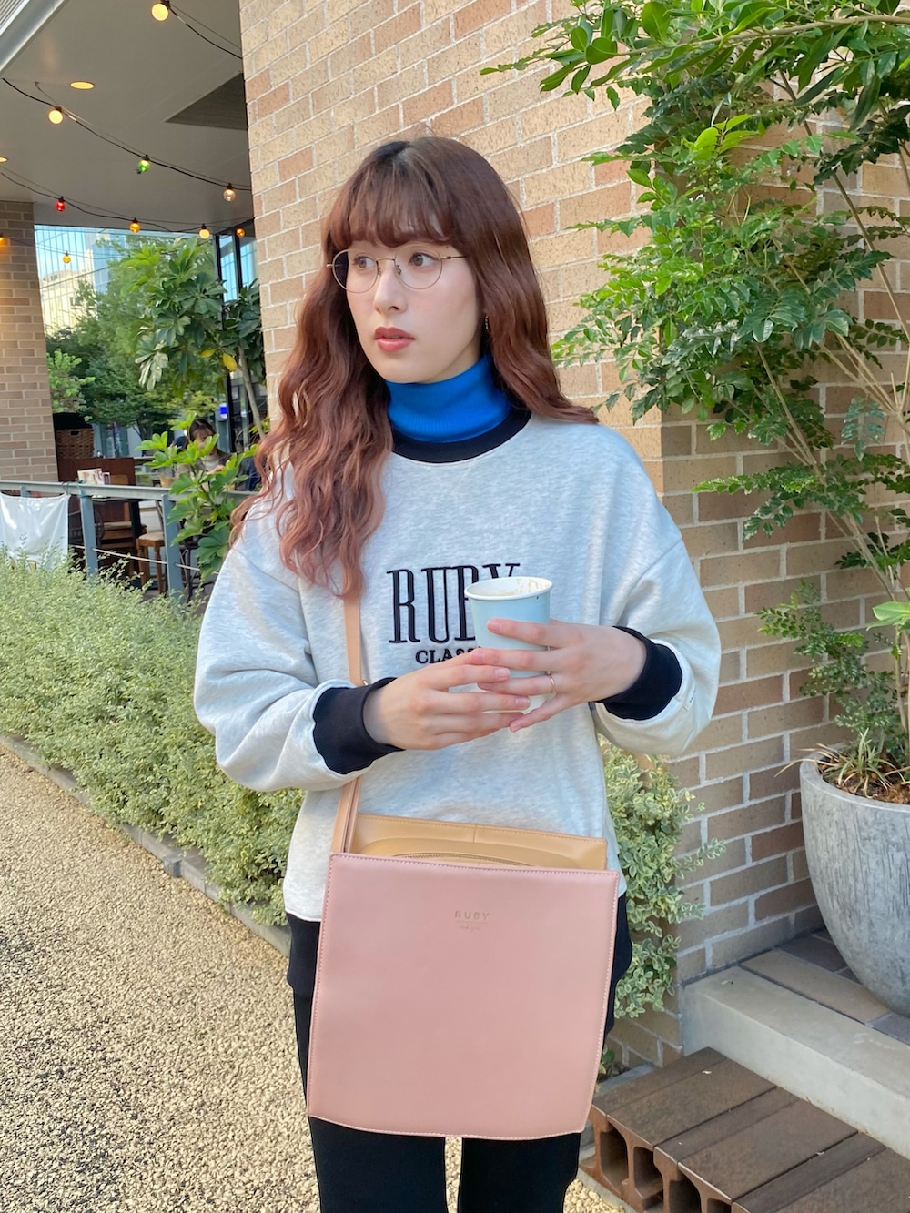 ブラック系のパンツ、ブラック系のスニーカー、ピンク系のショルダーバッグを着用したレディースの秋コーディネートの3枚目の写真