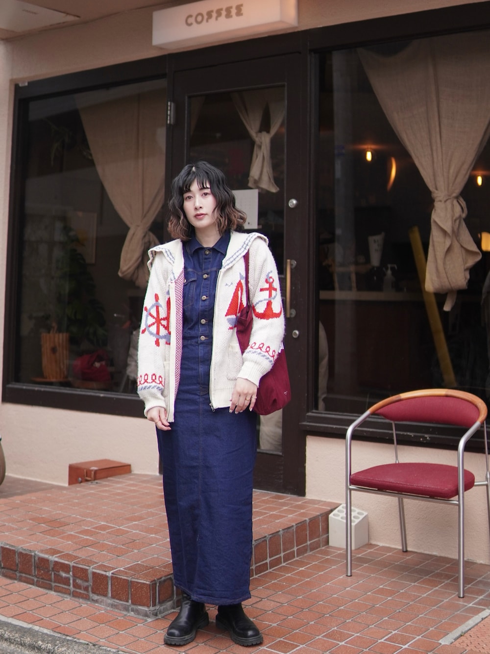 ブラック系のブーツ、ブルー系のワンピース、レッド系のトートバッグを着用したレディースの冬コーディネートの2枚目の写真