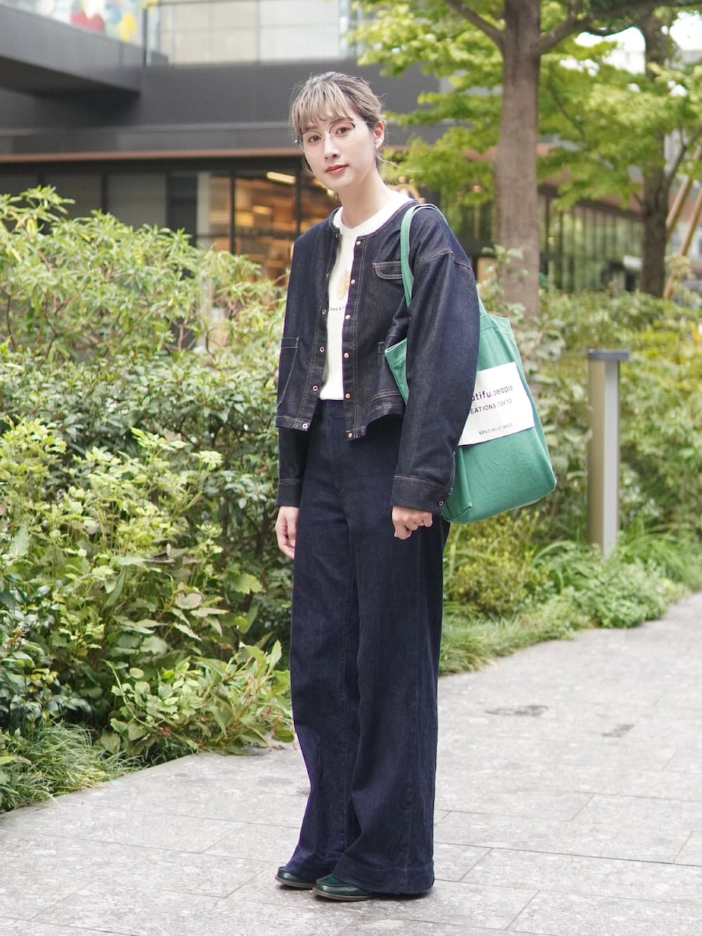 ブルー系のデニムジャケット、グリーン系のトートバッグ、ホワイト系のTシャツ/カットソーを着用したレディースの秋コーディネートの2枚目の写真