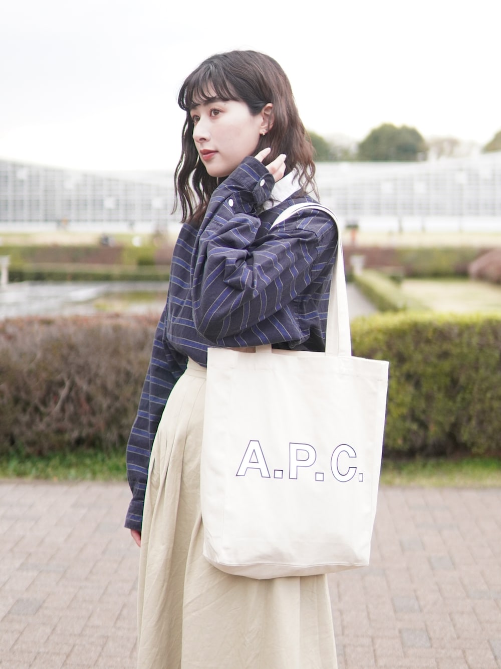 ベージュ系のスカート、ブラウン系のローファー、ブラック系のトートバッグを着用したレディースの春コーディネートの3枚目の写真