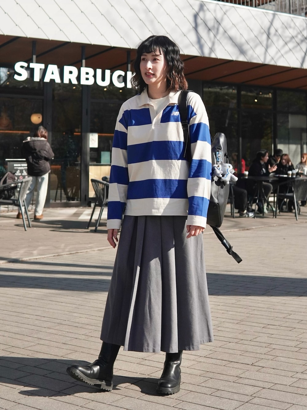 ブルー系のポロシャツ、ブラック系のブーツ、グレー系のスカートを着用したレディースの冬コーディネートの2枚目の写真