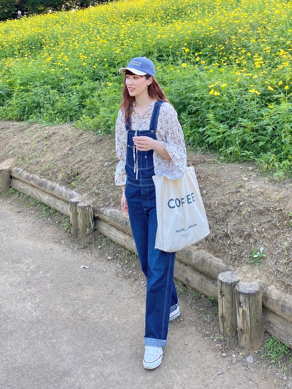 ホワイト系のスニーカー、ブルー系のサロペット/オーバーオール、ホワイト系のシャツ/ブラウスを着用したレディースの秋コーディネートの2枚目の写真