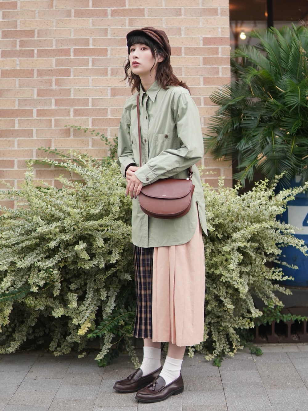 グリーン系のシャツ/ブラウス、ブルー系のスカート、ブラウン系のショルダーバッグを着用したレディースの秋コーディネートの2枚目の写真