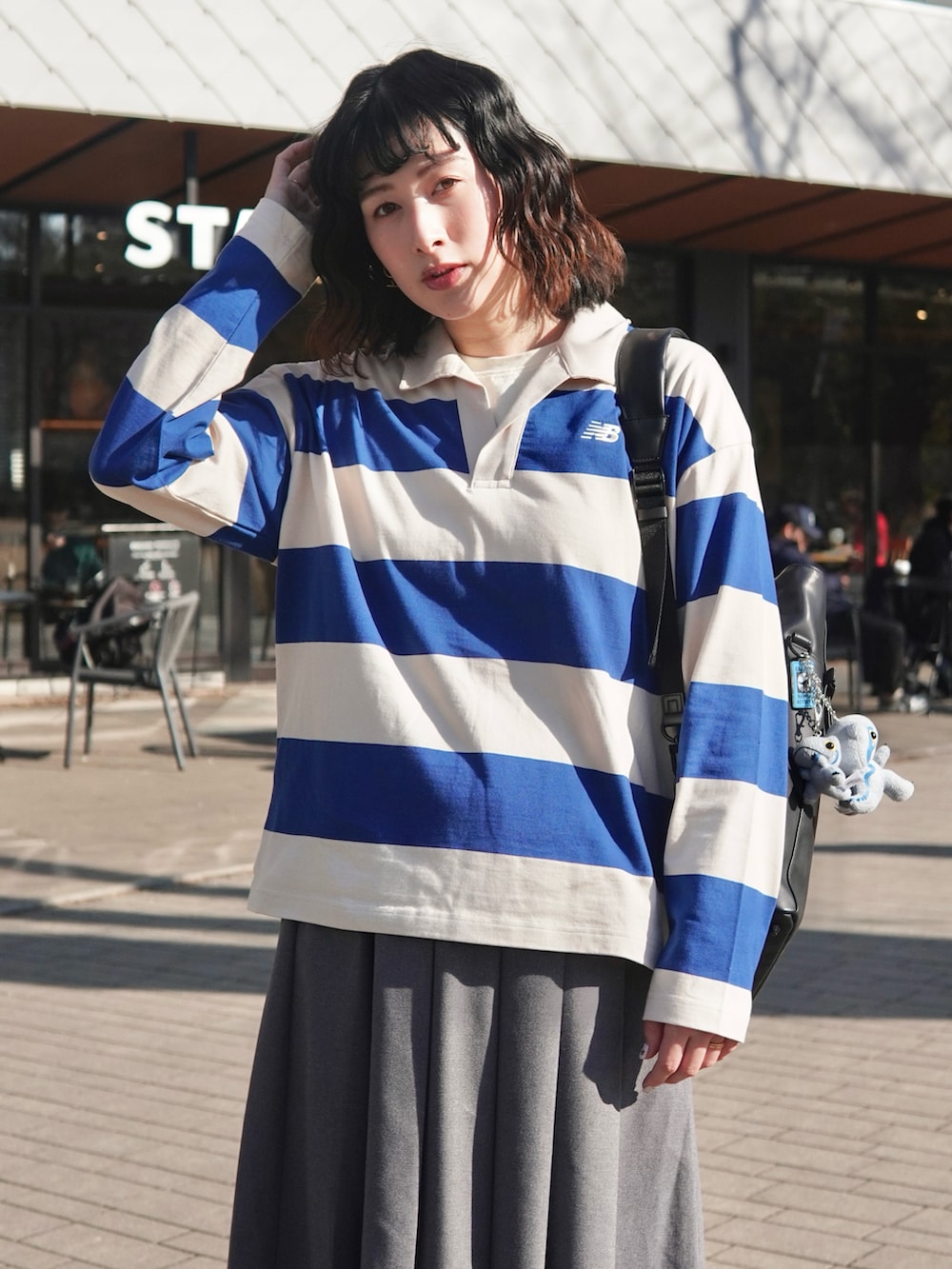 ブルー系のポロシャツ、ブラック系のブーツ、グレー系のスカートを着用したレディースの冬コーディネートの3枚目の写真