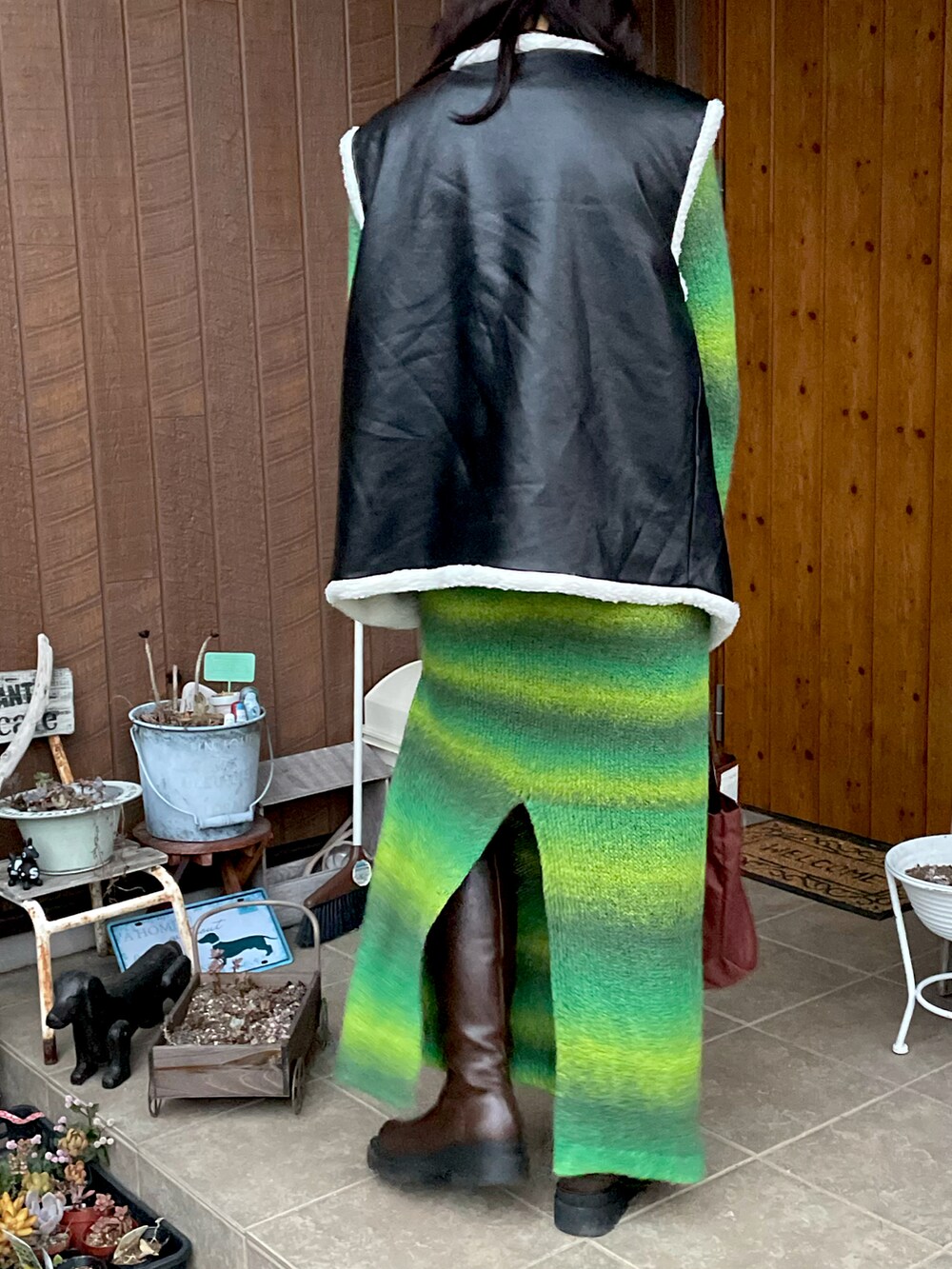 グリーン系のワンピース、ブラック系のその他アウター、ブラウン系のブーツを着用したレディースの秋コーディネートの3枚目の写真