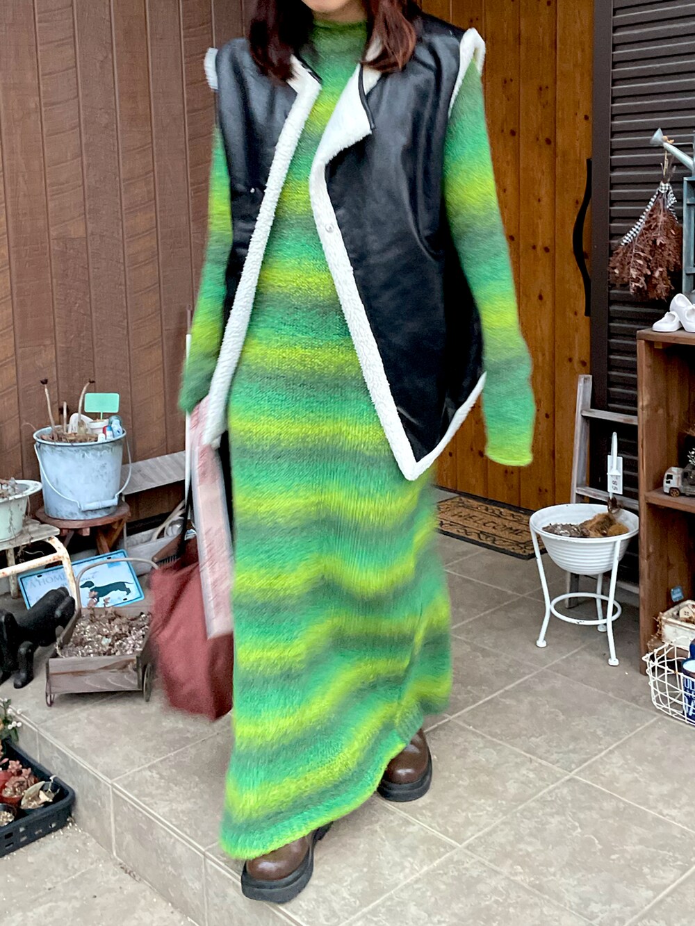 グリーン系のワンピース、ブラック系のその他アウター、ブラウン系のブーツを着用したレディースの秋コーディネートの2枚目の写真