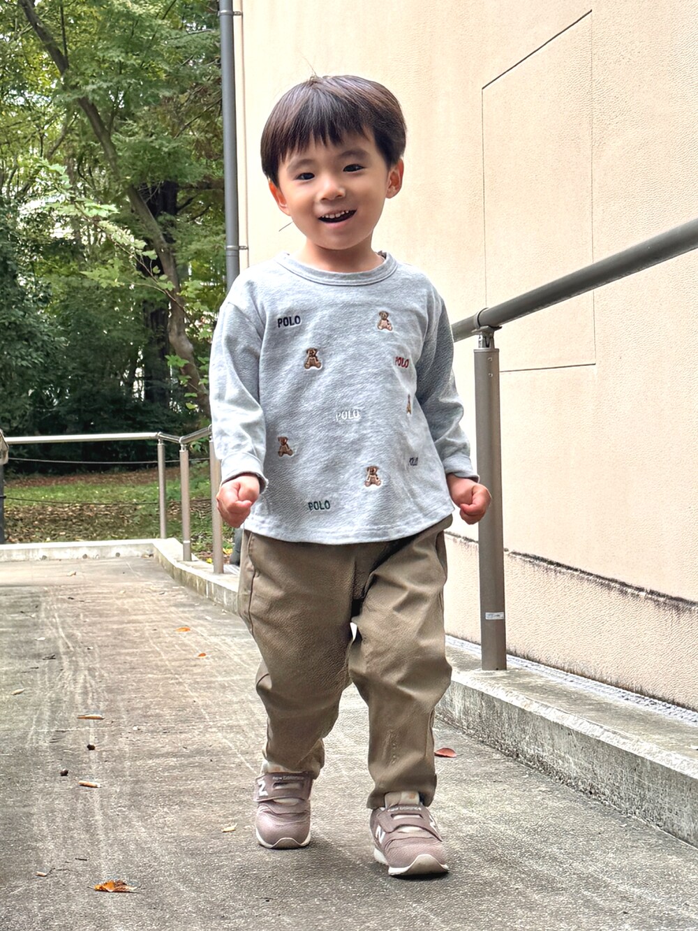 ベージュ系のチノパンツ、ブラウン系のスニーカー、ブルー系のカバーオールを着用したキッズの秋コーディネートの2枚目の写真