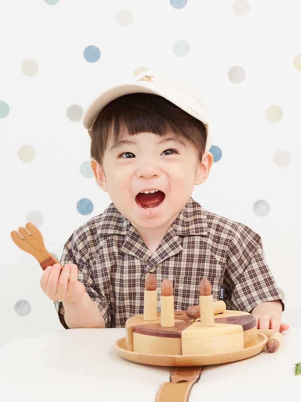 イエロー系のロンパース、ホワイト系のキャップを着用したキッズの秋コーディネートの2枚目の写真
