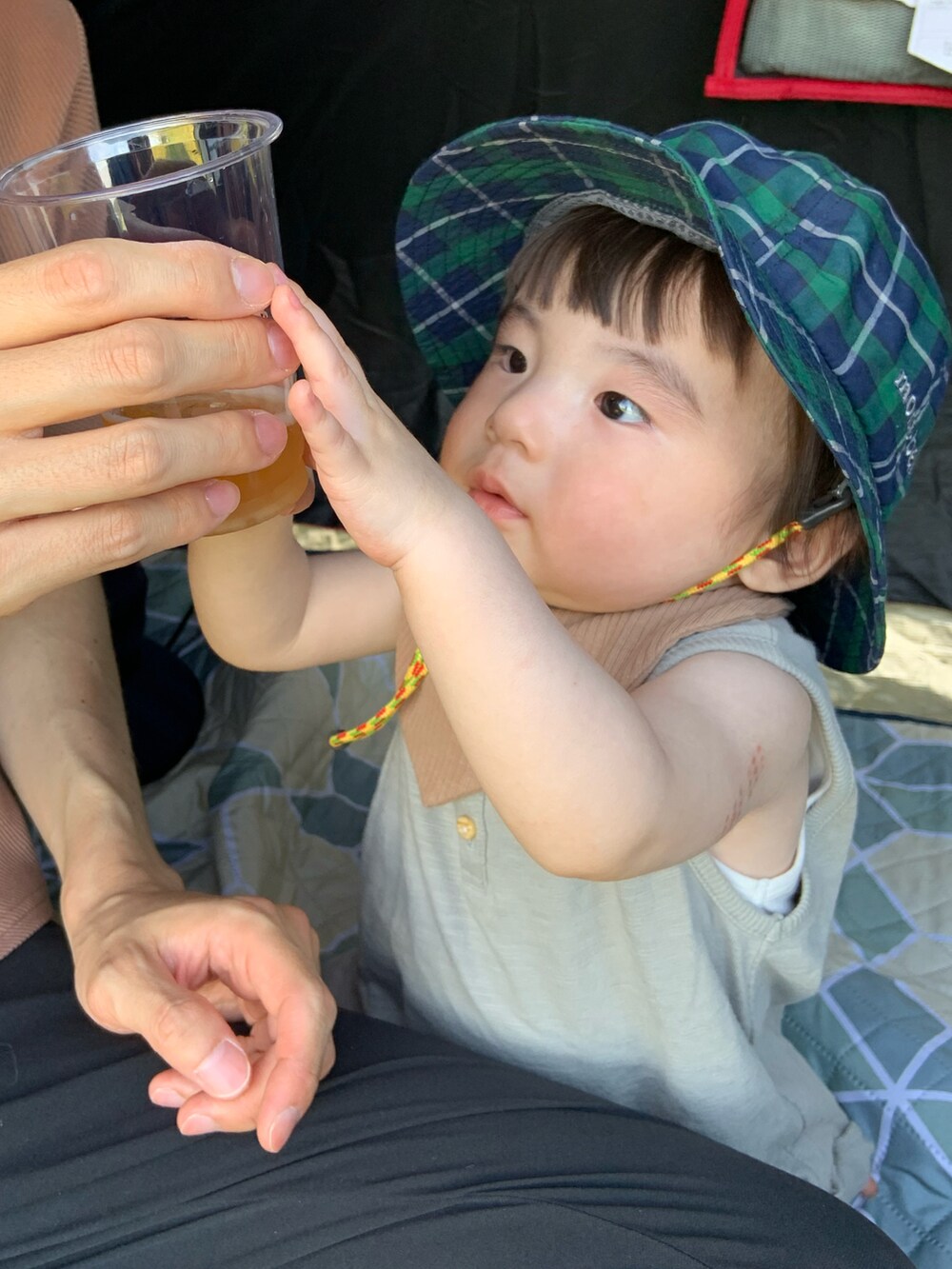 グリーン系のハット、ブラウン系のスタイ/よだれかけ、グリーン系のロンパースを着用したキッズの春コーディネートの2枚目の写真