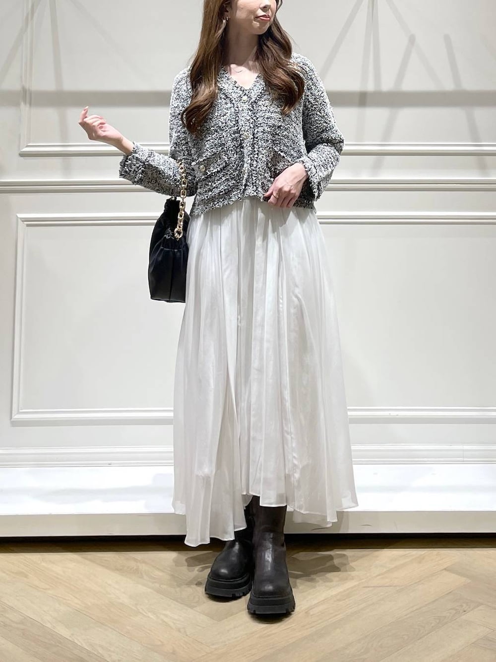 ブラック系のショルダーバッグ、ホワイト系のスカート、ブラック系のカーディガン/ボレロを着用したレディースの冬コーディネートの2枚目の写真