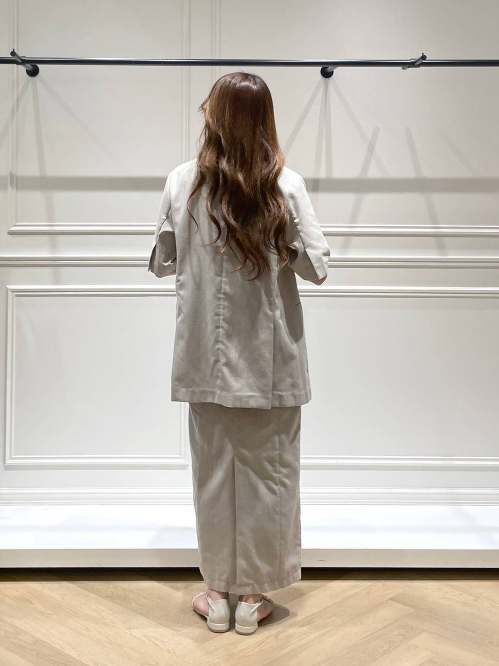 ホワイト系のハンドバッグ、ホワイト系のサンダル、ベージュ系のノーカラージャケットを着用したレディースの春コーディネートの4枚目の写真