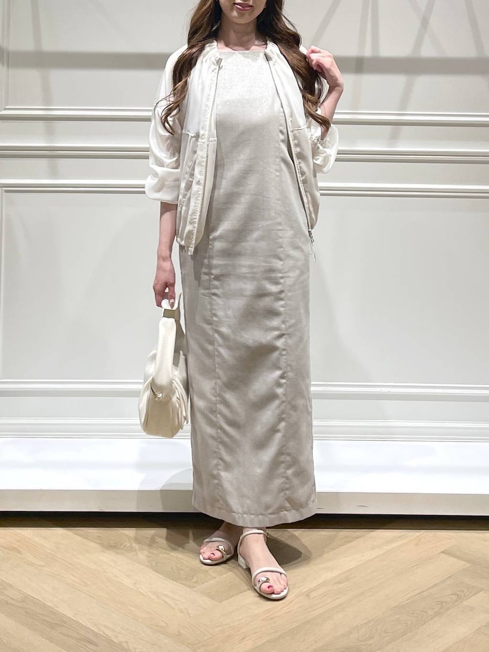 ホワイト系のハンドバッグ、ホワイト系のブルゾン、ホワイト系のサンダルを着用したレディースの春コーディネートの2枚目の写真