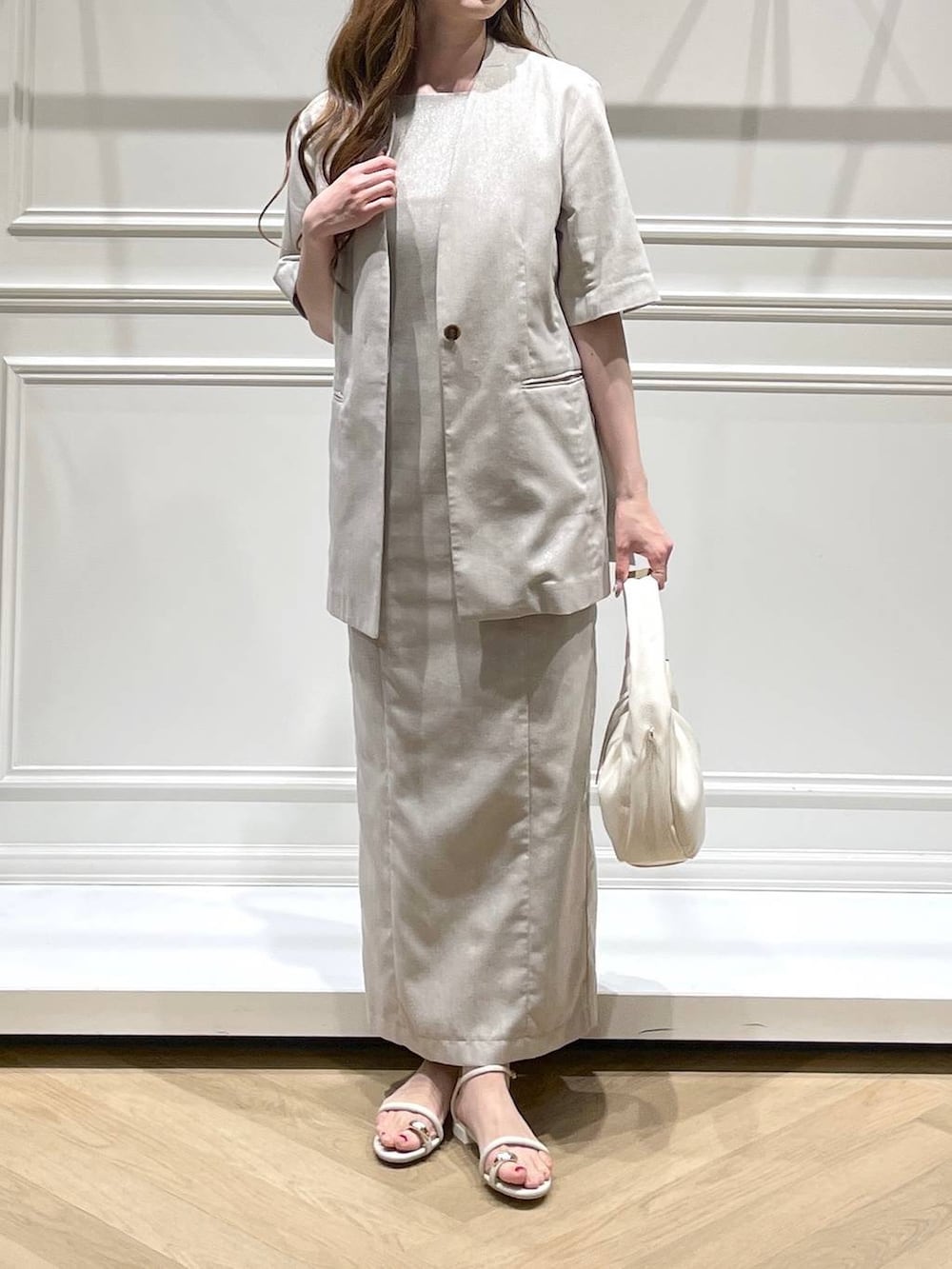 ホワイト系のハンドバッグ、ホワイト系のサンダル、ベージュ系のノーカラージャケットを着用したレディースの春コーディネートの2枚目の写真