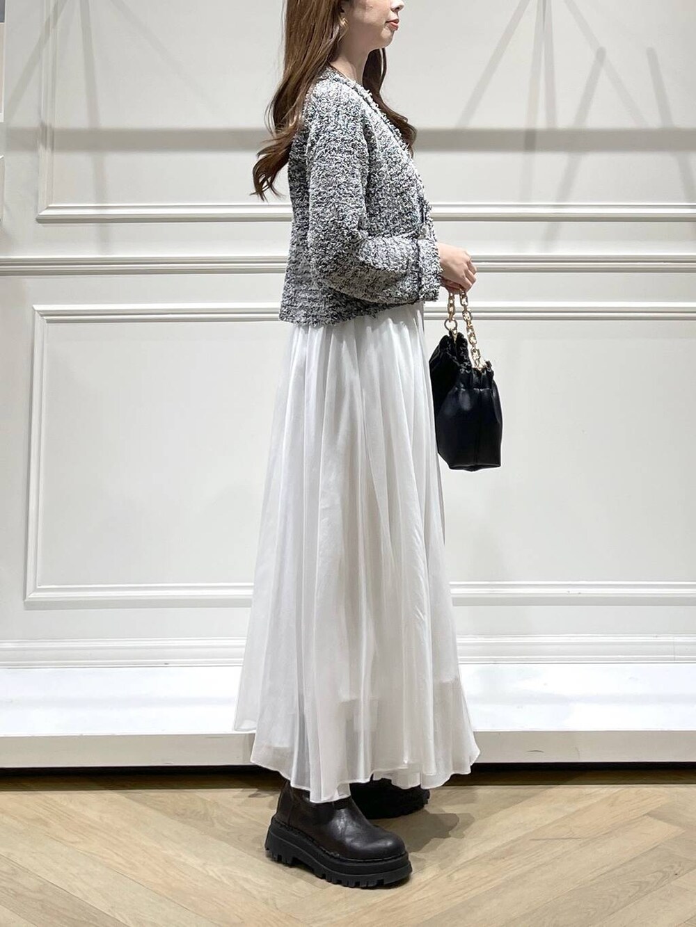 ブラック系のショルダーバッグ、ホワイト系のスカート、ブラック系のカーディガン/ボレロを着用したレディースの冬コーディネートの3枚目の写真