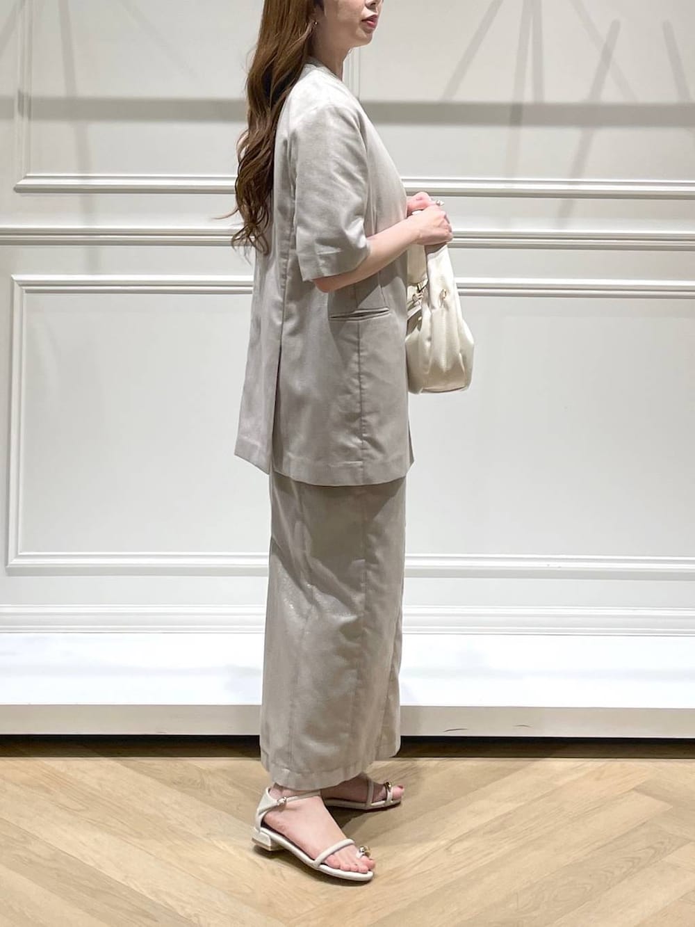 ホワイト系のハンドバッグ、ホワイト系のサンダル、ベージュ系のノーカラージャケットを着用したレディースの春コーディネートの3枚目の写真