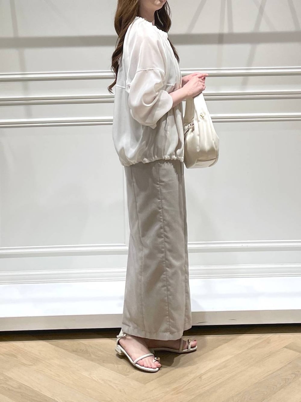 ホワイト系のハンドバッグ、ホワイト系のブルゾン、ホワイト系のサンダルを着用したレディースの春コーディネートの3枚目の写真