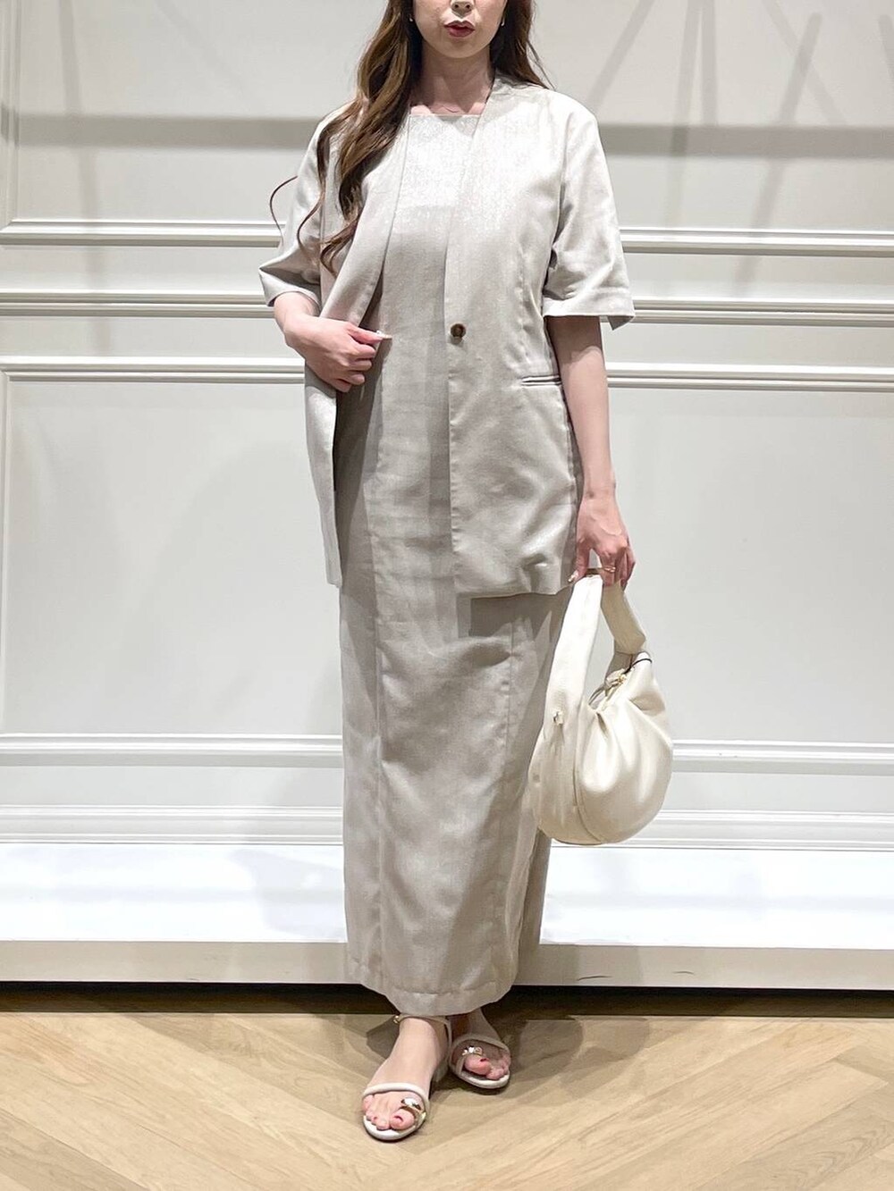 ホワイト系のハンドバッグ、ホワイト系のサンダル、ベージュ系のノーカラージャケットを着用したレディースの春コーディネートの5枚目の写真