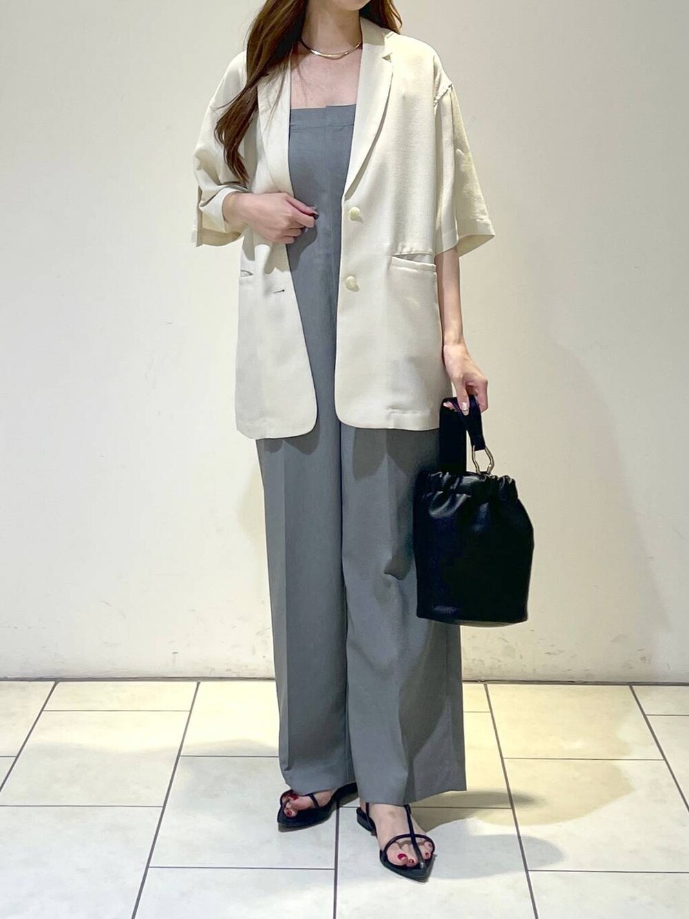グレー系のサロペット/オーバーオール、ホワイト系のテーラードジャケット、ブラック系のサンダルを着用したレディースの夏コーディネートの2枚目の写真